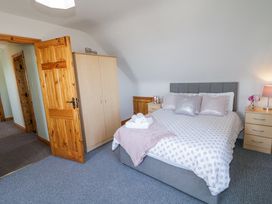 A bedroom with a double bed two bedside tables a wardrobe and an open wooden door at Tullyally in Redcastle