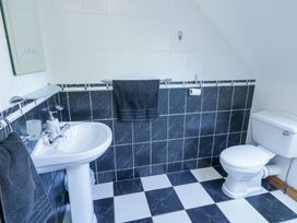 A bathroom with a pedestal sink a toilet black and white tiled walls and floor and black towels at Tullyally in Redcastle