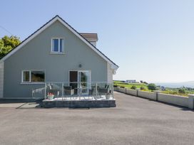 A house with a small patio with chairs and flowerpots overlooking a rural landscape at Tullyally in Redcastle