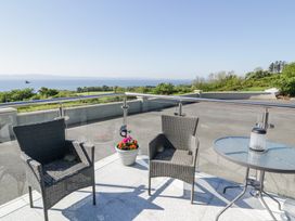 A balcony with two wicker chairs a glass table with a lantern and flowers in a pot overlooking greenery and water at Tullyally in Redcastle