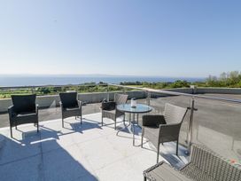 An outdoor terrace with a glass table and wicker chairs overlooking a body of water at Tullyally in Redcastle