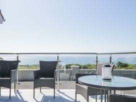 Outdoor balcony with glass railing wicker chairs and a round glass table with a lantern at Tullyally in Redcastle