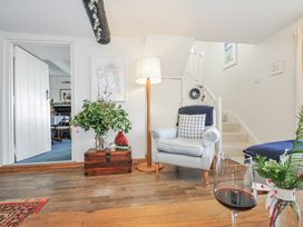A living room with a chair, lamp, and flower vase at Clamoak Cottage near Bere Alston