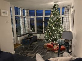 A living room with a Christmas tree and presents at Clamoak Cottage near Bere Alston