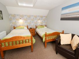 A bedroom with two single beds and a chair at Old Farmhouse Cottage