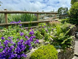 A garden with flowers and ferns next to a wooden fence at Old Farmhouse Cottage