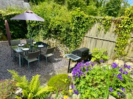 A garden with a table and chairs under an umbrella at Old Farmhouse Cottage