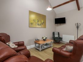 A living room with leather furniture and a television at Coetsiws in Clynnog Fawr