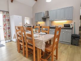 A kitchen with dining table and appliances at Coetsiws in Clynnog Fawr