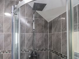 A shower with a glass enclosure and tiled walls at Coetsiws in Clynnog Fawr