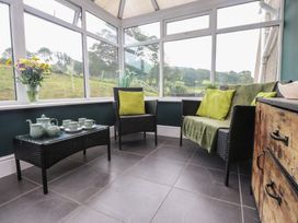 A conservatory with chairs and a coffee table at Coetsiws in Clynnog Fawr
