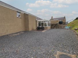 A garden area with a conservatory and dining table at Coetsiws in Clynnog Fawr