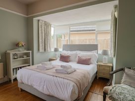 A bedroom with a bed, nightstands, and windows at Sunny Croft in Broadmayne near Dorchester