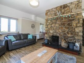 A living room with a stone wall and sofa at Tyn Morfa in Llangwnnadl near Aberdaron