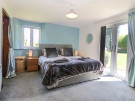 A bedroom with a bed and sliding doors at Tyn Morfa in Llangwnnadl near Aberdaron