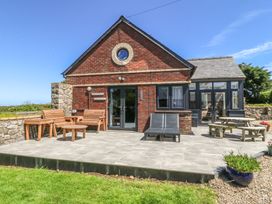 A house with patio furniture and a stone wall at Tyn Morfa in Llangwnnadl near Aberdaron