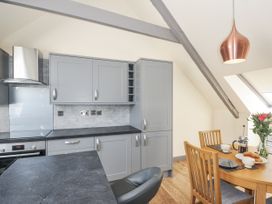 A kitchen with cabinets and dining table at Beach Retreat in Looe