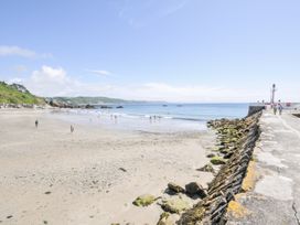 A beach with people walking along the shore at Beach Retreat in Looe