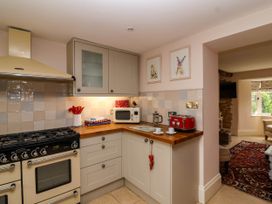 A kitchen with a stove microwave red toaster and utensils at Puffitts Cottage in Bourton-on-the-Water