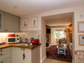 A kitchen with appliances and a view into the living room at Puffitts Cottage in Bourton-on-the-Water