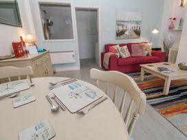A living room with a red sofa and dining area at Beachcomber in Marazion
