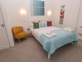 A bedroom with a bed, chair, and wall art at Beachcomber in Marazion