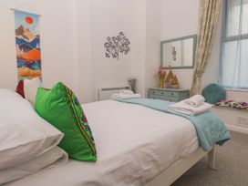 A bedroom with a bed, mirror, and decorative items at Beachcomber in Marazion
