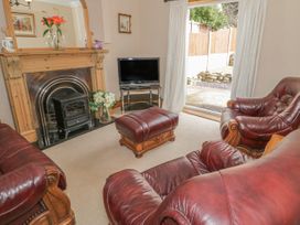 A living room with leather armchairs a fireplace and a television near a sliding glass door at Jasmine Cottage in Rhuddlan