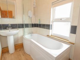 A bathroom with a bathtub shower sink and a window at Jasmine Cottage in Rhuddlan