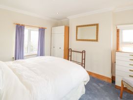 A bedroom with a bed white bedding blue curtains a wardrobe a dresser and a mirror at Jasmine Cottage in Rhuddlan