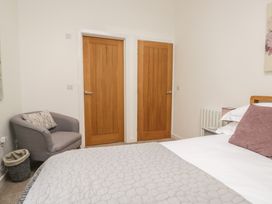 A bedroom with two doors and a chair at Coney Garth Barn in Beckermet
