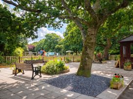 A garden with benches, a playground and flowerbeds at Coney Garth Barn in Beckermet