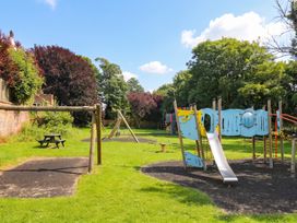 A playground with swings and a slide at Coney Garth Barn in Beckermet