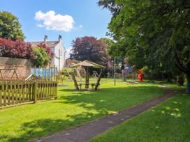 A playground with swings and a slide at Coney Garth Barn in Beckermet