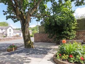 A garden area with a tree, flower bed, and bench at Coney Garth Barn in Beckermet