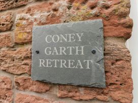A slate sign with Coney Garth Retreat on a brick wall at Coney Garth Retreat Beckermet