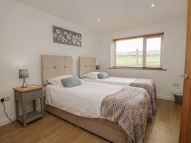 A bedroom with two beds and a bedside table at Coney Garth Retreat in Beckermet