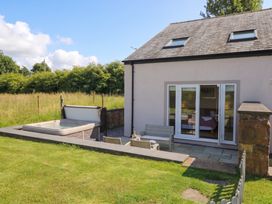 A patio area with a hot tub and outdoor furniture at Coney Garth Retreat in Beckermet