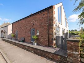 An outdoor view of a house with a brick wall and garden at Coney Garth Retreat in Beckermet