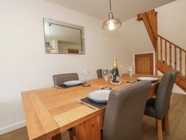 A dining room with a table set and a staircase at Coney Garth Cottage in Beckermet