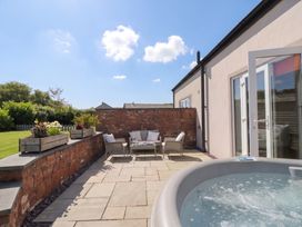 An outdoor area with a hot tub and seating at Coney Garth Cottage in Beckermet