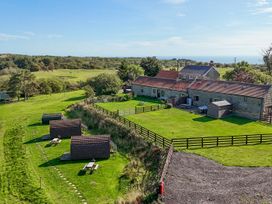 An outdoor view with cabins and a farmhouse at Carters in Staintondale