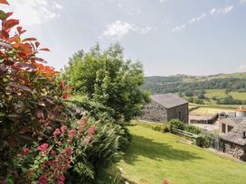 A garden with flowers and stone buildings at Rose Cottage Broughton-In-Furness