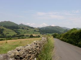A landscape with fields and a stone wall alongside a road at Rose Cottage in Broughton-In-Furness
