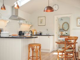 A kitchen with a stove and table at The Coach House at Pendower House in Fowey