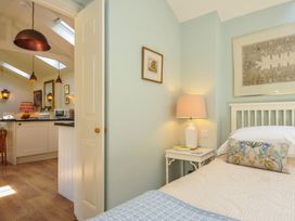 A bedroom with a bed and side table leading to a kitchen at The Coach House at Pendower House Fowey