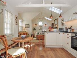 A kitchen with appliances and seating area at The Coach House at Pendower House Fowey