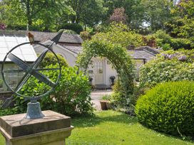 A garden with a compass and ornamental arch at The Coach House at Pendower House in Fowey
