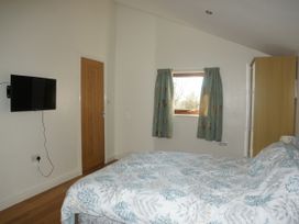 A bedroom with a bed and television at Dilly Dally Barn in Bradworthy near Bude