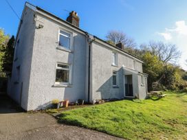 An exterior view of a white two-story house with multiple windows and a lawn with a picnic table near Pengraig near Tregaron